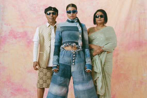 junge Frau aus Bangladesch in Jeans-Outfit und Sonnenbrille, ihre Eltern stehen hinter ihr und tragen Sonnenbrillen.