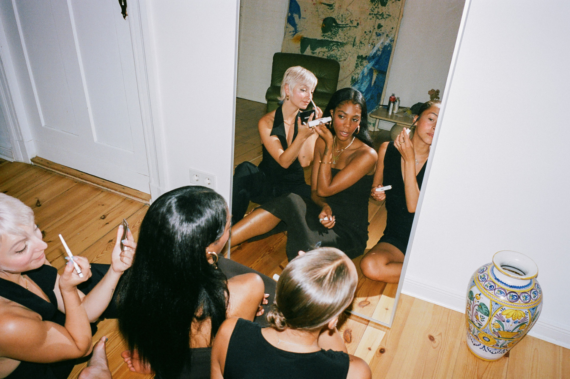 Eine Gruppe an Frauen, die vor einem Spiegel sitzt und sich mit tierversuchsfreier Kosmetik schminkt